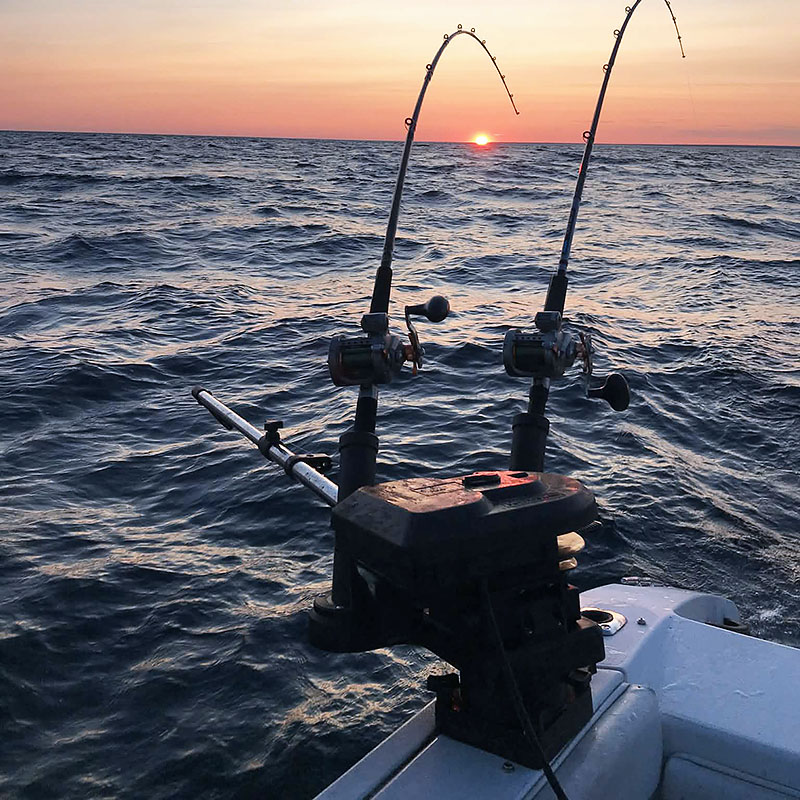 Image taken by Richard Panton of two fishing rods casted from a boat at sunset.