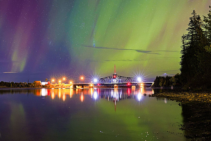 Image taken by Craig Jackson of the Little Current crossing bridge lit up at night during a northern lights display