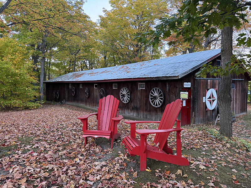 Image taken by Dawn Noble McCann of two Adirondack chairs in front of an ornate barn in the Fall.