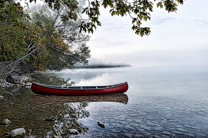 Image taken by Craig Jackson of a canoe sitting on the shore of a lake.