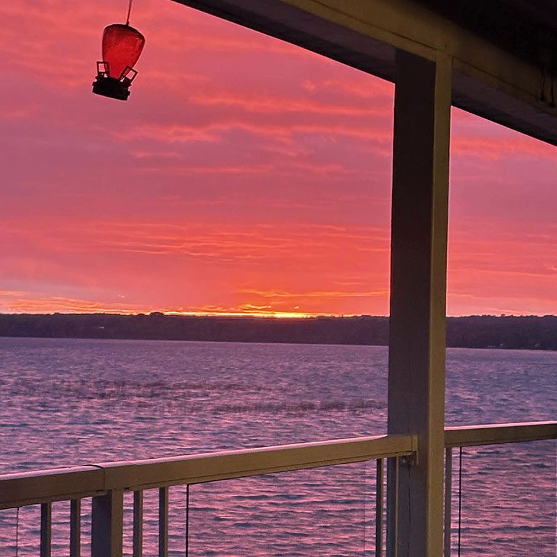 Image taken by Richard Panton of a sunset viewed from a cabin porch by a lake