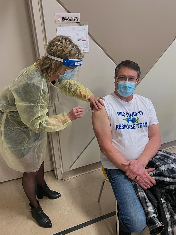 Image of Nurse Paula administering the COVID-19 vaccination to Mike